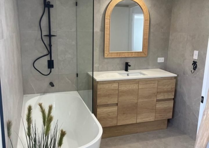 Modern bathroom with tub and wood vanity.