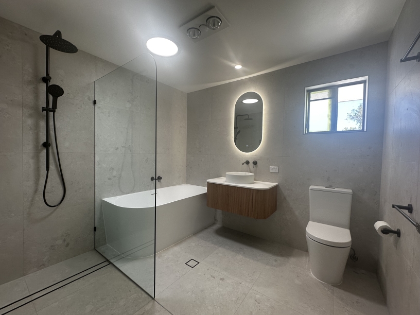 Modern bathroom with bathtub, shower, and oval mirror