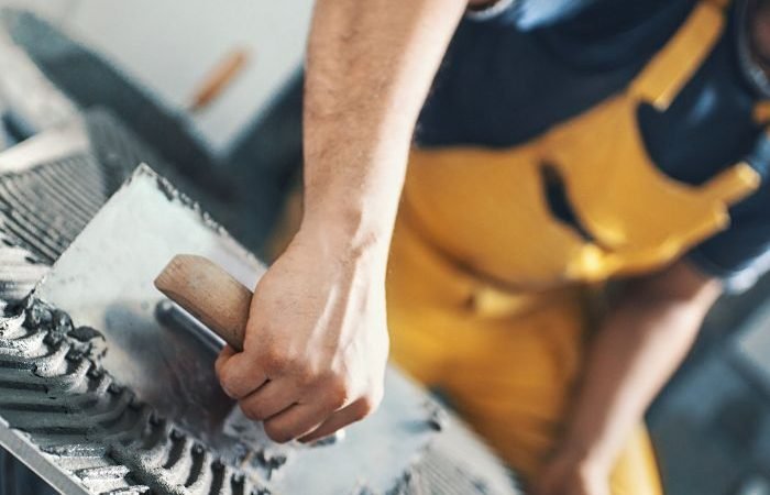 Worker smoothing cement with trowel