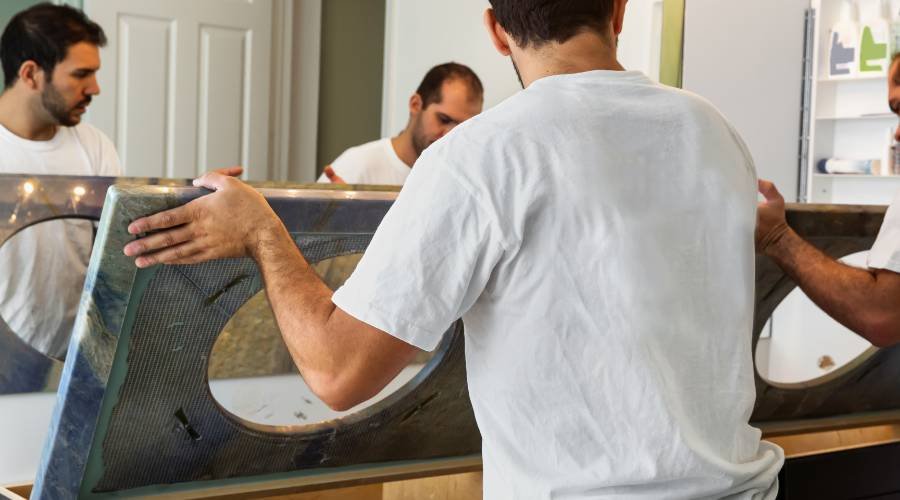 Three men installing large mirror indoors.