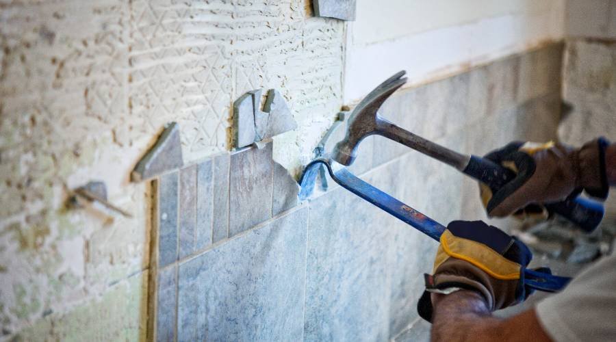 Removing wall tiles with hammer and crowbar.