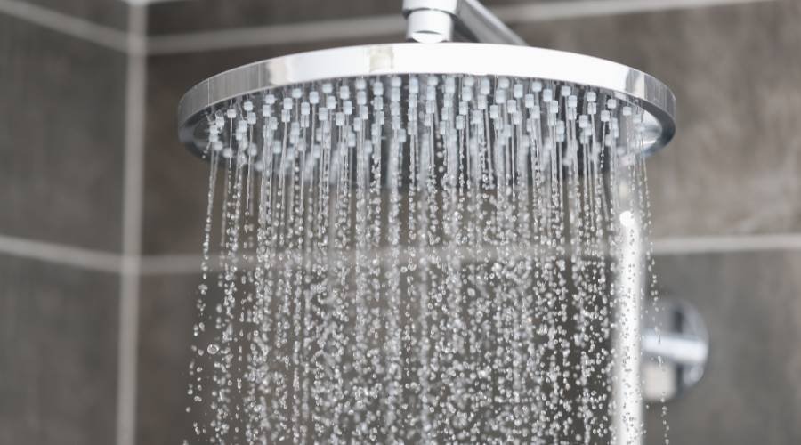 Showerhead with flowing water in modern bathroom.