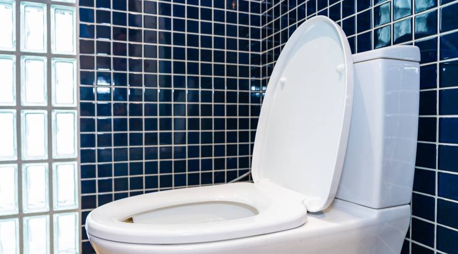 White toilet with blue tile wall background.