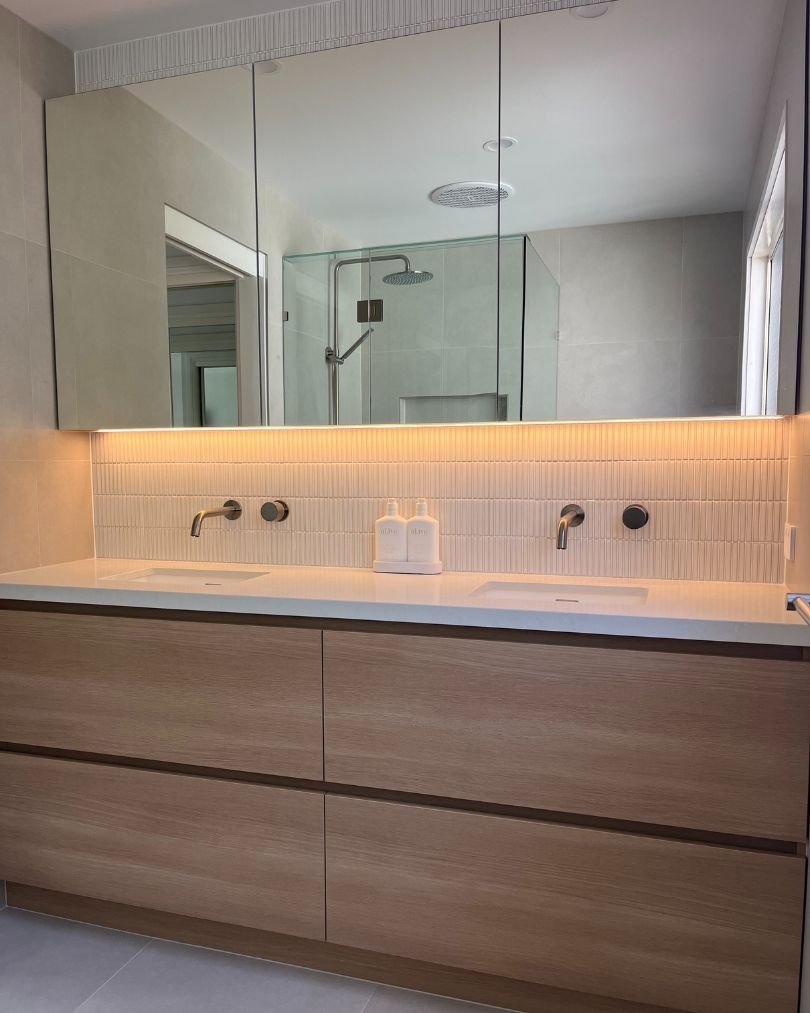 Modern bathroom with double vanity and mirrors.