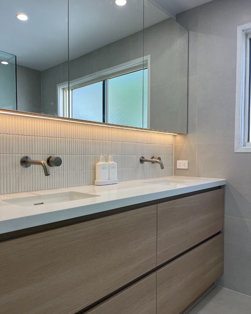 Modern bathroom with dual sinks and storage cabinets.