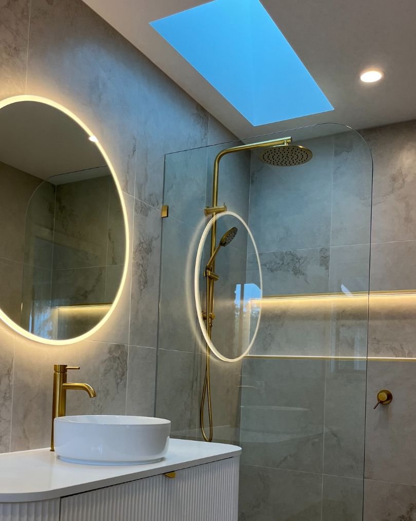 Modern bathroom with circular mirror and skylight