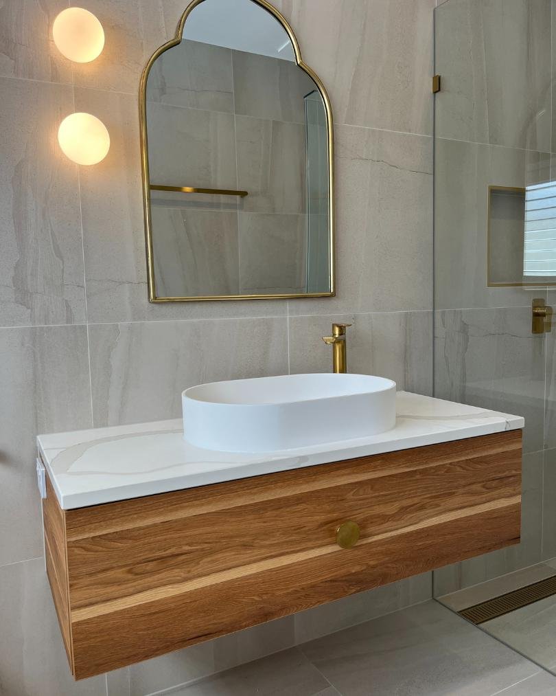 Modern bathroom with wooden vanity and oval sink.