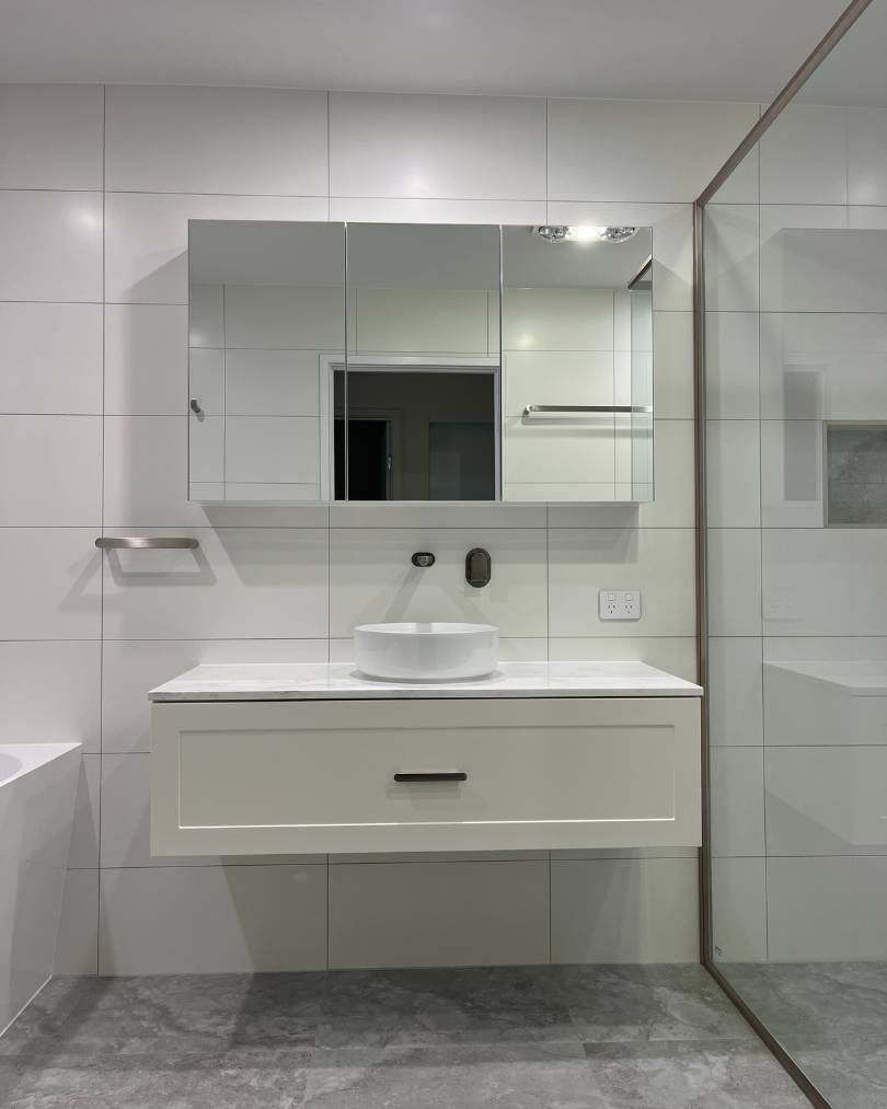 Modern bathroom with white tiles and vanity.