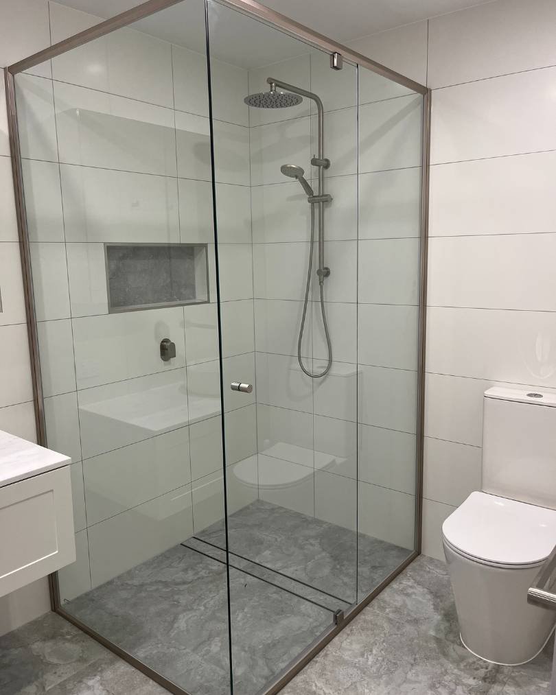 Modern bathroom with glass shower and toilet.