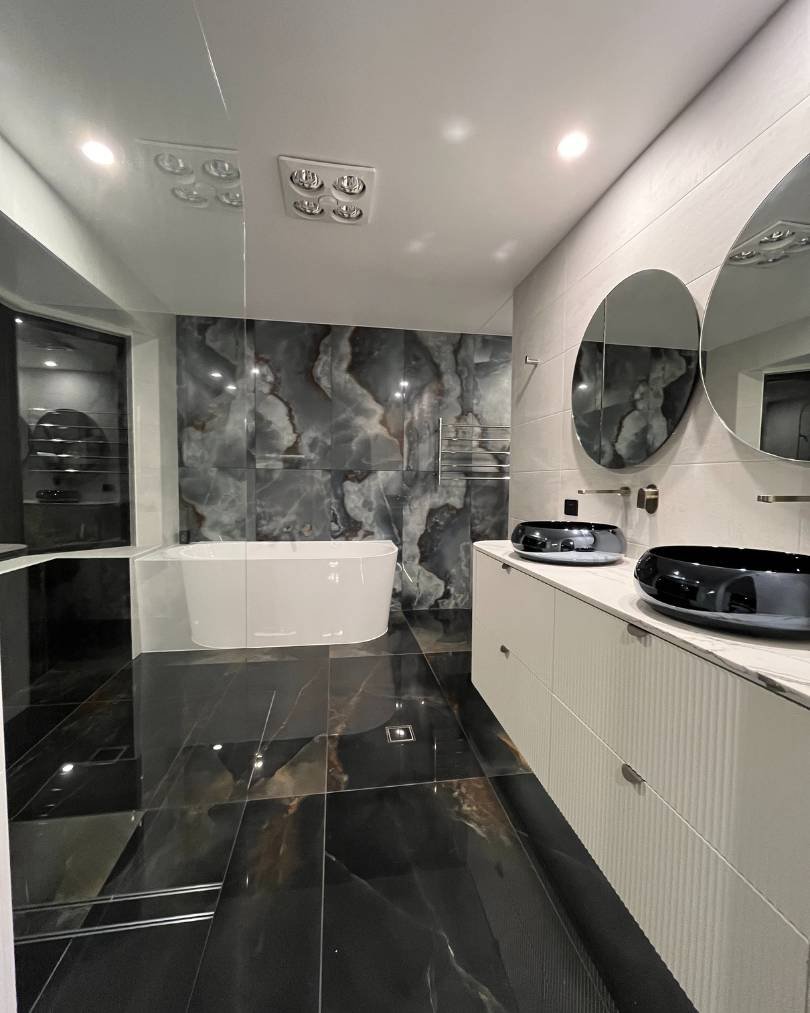 Modern bathroom with black marble floor and mirrors.